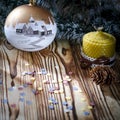 A gift lays on a wooden table next to a candle, cones and an angel against the background of Christmas decorations Royalty Free Stock Photo