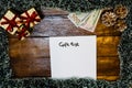 Gift list writing on paper. Christmas decorations on wooden board. Christmas concept. Money on table for buying Christmas gifts Royalty Free Stock Photo