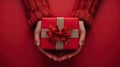 Gift of Love: Woman\'s hands holding luxury box with bow in top down view against a vibrant red backdrop