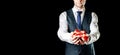 Gift man. Happy young businessman holding surprise gift box present with red ribbon isolated on black background. Black Royalty Free Stock Photo