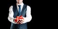 Gift man. Happy young businessman holding surprise gift box present with red ribbon isolated on black background. Black Royalty Free Stock Photo