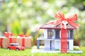 Gift new home and Real estate concept,Model house with Red ribbon and the car on natural green background Royalty Free Stock Photo