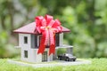 Gift new home and Real estate concept,Model house with Red ribbon and the car on natural green background Royalty Free Stock Photo