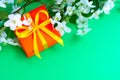 Gift orange box yellow bow white flowers green desk background Royalty Free Stock Photo