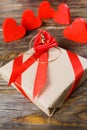 The gift is Packed in Kraft paper and tied with a red ribbon with a rose in the center of which lies a pendant in the shape of clo Royalty Free Stock Photo