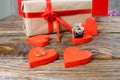 The gift is Packed in Kraft paper and tied with a red ribbon rose. Gift surrounded by decorative hearts one is a wedding ring with Royalty Free Stock Photo