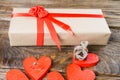 The gift is Packed in Kraft paper and tied with a red ribbon rose. Gift surrounded by decorative hearts one is a wedding ring with Royalty Free Stock Photo