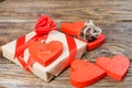 The gift is Packed in Kraft paper and tied with a red ribbon rose. Gift surrounded by decorative heart on one are wedding rings on Royalty Free Stock Photo