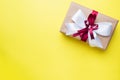 Gift or present box with a big bow on a yellow table top view. Flatlay composition for Christmas birthday, mother day or wedding Royalty Free Stock Photo