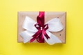 Gift or present box with a big bow on a yellow table top view. Flatlay composition for Christmas birthday, mother day or wedding Royalty Free Stock Photo
