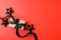 Gift or present box with black satin ribbon bow on red table top view. Flat lay composition for birthday, mother day, black friday Royalty Free Stock Photo