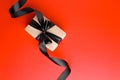 Gift or present box with black satin ribbon bow on red table top view. Flat lay composition for birthday, mother day, black friday Royalty Free Stock Photo