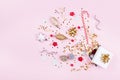 Gift or present box with confetti stars, golden ribbon and holiday decoration on pastel pink background. Christmas flat lay. Royalty Free Stock Photo