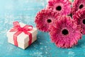 Gift or present box for mother or womans day decorated with beautiful gerbera daisy flowers on vintage wooden background.