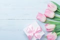 Gift or present box and pink tulip flowers on blue wooden table top view. Greeting card for Womans or Mothers Day. Flat lay. Royalty Free Stock Photo