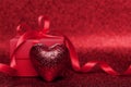 Gift or present box with red bow ribbon and heart on sparkling backdrop for Valentines day. Royalty Free Stock Photo
