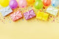 Gift or present boxes, colorful balloons and confetti on pastel table top view. Birthday party background