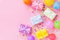 Gift or present boxes, colorful balloons and confetti on pink pastel table top view. Birthday party background. Banner format