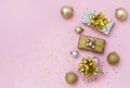 Gift or present boxes with gold bows, Christmas balls and confetti on a pink background, top view. Greeting card with copy space Royalty Free Stock Photo