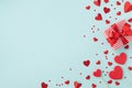 Gift or present wirh red ribbon and various hearts on blue table top view. Valentine day card Royalty Free Stock Photo