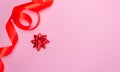 Gift red bow on a pink background and red satin ribbon on the side. Free space for text. Holidays, Christmas, Valentine`s Day Royalty Free Stock Photo