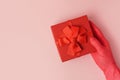 A gift in a red box in the hand of a woman in red rubber glove