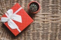 Gift red box with white ribbon on woven bamboo background cozy and warm home welcome concept idea and small lovely green cactus Royalty Free Stock Photo