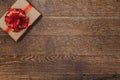 Gift with a red ribbon and bow on a dark wooden background