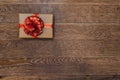 Gift with a red ribbon and bow on a dark wooden background