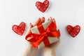 Gift with a red ribbon in hands on a white background