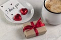 A gift with a red ribbon, a mug of coffee, heart-shaped chocolates and a note with the word I love you. Valentine`s day breakfast Royalty Free Stock Photo