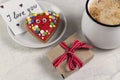 Gift with red ribbon, mug of coffee, heart shaped gingerbread and a note with the word I love you . Valentine`s Day breakfast Royalty Free Stock Photo