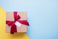 gift with red satin ribbon and blank tag on yellow and blue background, copy space Royalty Free Stock Photo