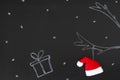 Gift and reindeer antlers drawn with chalk on blackboard with Santa Claus hat, creative concept christmas background