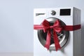 Gift ribbon on a new washing machine on white background. ai generative Royalty Free Stock Photo