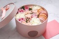 Gift round box with flowers, roses and macaroons almond cake with pink envelope on the table