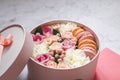 Gift round box with flowers, roses and macaroons almond cake with pink envelope on the table