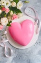 Gift set - pink heart-shaped mousse cake and a large bouquet of beautiful flowers on the grey grunge background. Valentine`s Day. Royalty Free Stock Photo