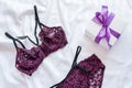 Gift, shopping and fashion concept. Set of glamorous stylish lace lingerie on bed with giftbox on white background