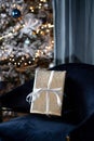 A gift in a silver wrapper with a white ribbon on a velvet blue chair Royalty Free Stock Photo