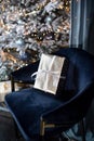 A gift in a silver wrapper with a white ribbon on a velvet blue chair Royalty Free Stock Photo