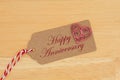 A gift tag on wood with a heart with text Happy Anniversary