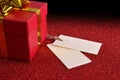 Gift with two tags on bright red textured table elevated Royalty Free Stock Photo