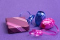 Gift in a violet box and a decorative ribbon next to a violet background