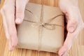 Gift wrapped in brown craft paper and tied with lace. Female hands holding small cardboard box. Birthday greeting with surprise Royalty Free Stock Photo