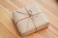 Gift wrapped in brown craft paper and tied with lace. Female hands holding small cardboard box. Birthday greeting with surprise Royalty Free Stock Photo