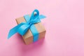 Gift wrapped and decorated with blue bow on pink background with copy space. Flat lay, top view Royalty Free Stock Photo