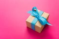 Gift wrapped and decorated with blue bow on pink background with copy space. Flat lay, top view Royalty Free Stock Photo