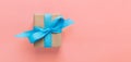 Gift wrapped and decorated with blue bow on pink background with copy space. Flat lay, top view Royalty Free Stock Photo