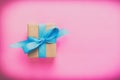 Gift wrapped and decorated with blue bow on pink background with copy space. Flat lay, top view Royalty Free Stock Photo